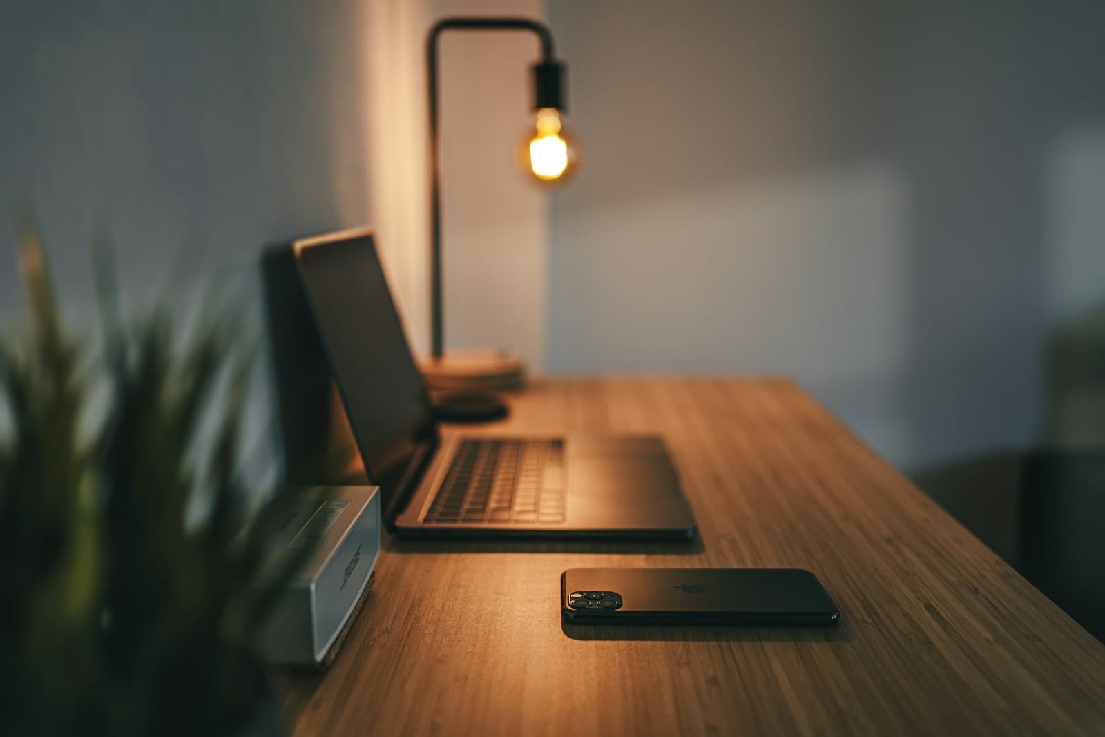 A warm contemporary desk with a laptop, lamp, and phone